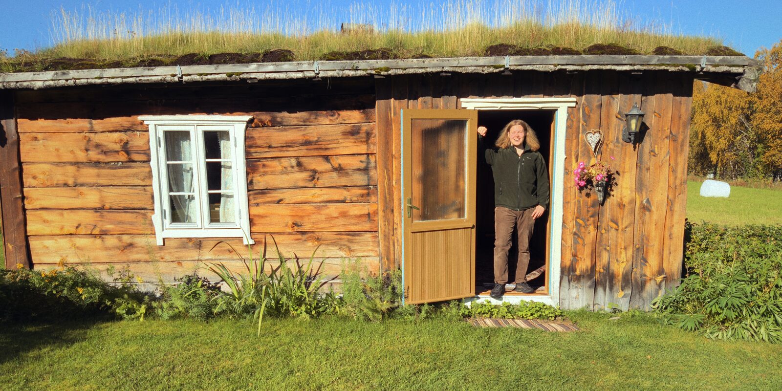 Gammelstua med torvtak på Øvre Sletten. Ole står i døra.