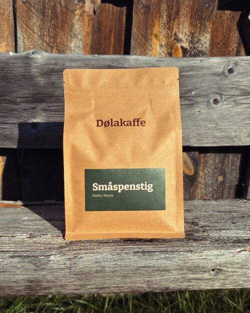 Småspenstig-posa står på en benk mot fjøsveggen. Grønn etikett på kraftpapir.